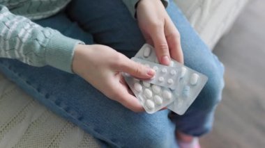 Top view young hands hold tablets while indoors, unrecognizable, close up. Doctor prescribed treatment. Person is mentally preparing to fulfill it.