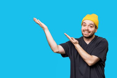 Studio portrait shot with copy space an american and expressive bearded man, looking at the camera with a joyful gesture and laughing expression. blue background