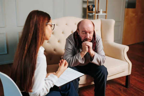 a bald senior man looking at a young nurse. Mature female psychiatrist communicating with sad 60s patients, senior worried, serious elderly, worried mature, stress, lonely, therapist, patient,