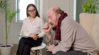 young psychologist taking notes while consulting depressed caucasian patient during therapy sessions at a cozy office. psychology, mental health and people concept, consultant grandfather,