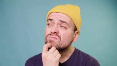 A studio shot of a male guy with a confused expression, making a funny face, as if hes trying to make a point. He looks like hes thinking hard, and has a question in his face. pondering something