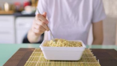 A close up shot of a fork in the hands of someone at home, savoring a steaming plate of showing instant noodles.