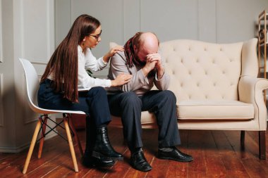 anxious troubled senior Caucasian bald man with caring young female nurse psychologist, Senior man therapy at home. rehabilitation therapy, physical therapist, physician consulting, upset, tired,