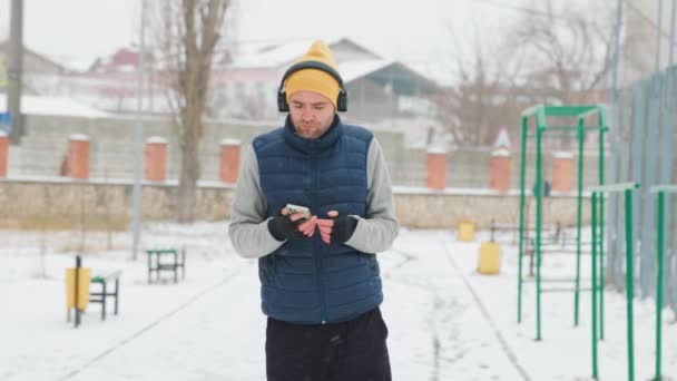 Shot Emphasizing Movement Strength Runner Headphones Smartphone Jogs Winter Terrain — Αρχείο Βίντεο
