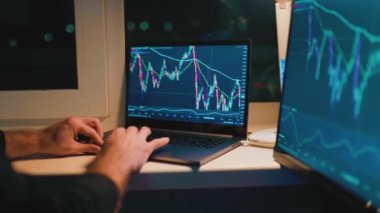 Finansal Gece Vardiyası gecenin sessizliğinde ticaretin ve ticaretin hızlı ilerleyen dünyasına ayak uydururken klavyeye yazı yazan bir adamın yakın çekimi..