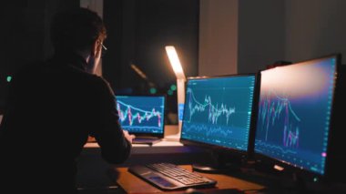 Finansal tahminlere göre, bir sonraki büyük döviz kurunu tahmin etmek için haritalar, grafikler ve şemalar kullanarak özenle çalışan bir erkek tüccar....