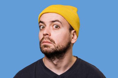 A guy with an uncertain expression, his face contorted in a grimace, captured in a studio shot while looking at the camera. Doubtful and Funny A Studio Shot of a Mans Facial Expressions