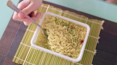 A imagine of a fork in the hands of someone indulging in fast food, with the kitchen in the background. with the kitchen in the background.