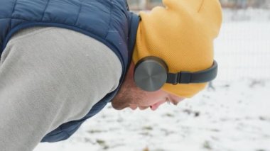 Snowy Jogger A guy with headphones he looks tired, he leans down jogs through the winter scene, his athletic abilities and energetic spirit on full display. Despite being tired from a long day,