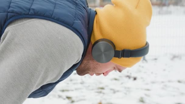 Snowy Jogger Facet Słuchawkami Wygląda Zmęczonego Pochyla Się Nad Sceną — Wideo stockowe