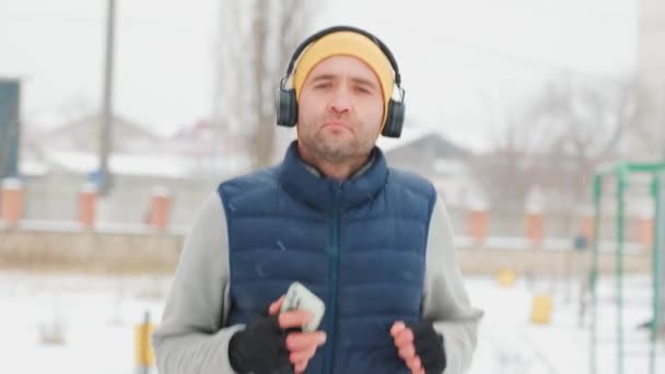 Genç Yetişkin Bir Erkek Kulaklık Takmış Elinde Akıllı Bir Telefonla — Stok video