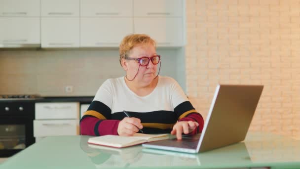 Старшая Женщина Своем Доме Использует Ноутбук Электронного Обучения Носит Очки — стоковое видео