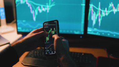 Akıllı telefon ve hesap makinesi ile parlayan bilgisayar ekranlarının birleşiminden elde ettiği yakın çekim ticaret ve yatırımın büyüleyici bir sahnesini oluşturuyor..
