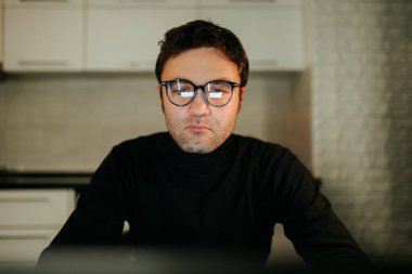 A close-up of a young adult male in a cozy home environment, the dim light of nighttime adding a peaceful atmosphere.