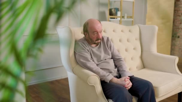 Strong Stoic Older Man Sits Sturdy Sofa Rustic Living Room — стоковое видео