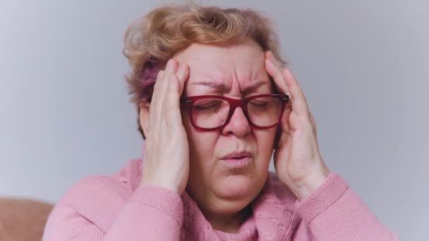 Ηλικιωμένη Γυναίκα Που Υποφέρει Από Έναν Εξουθενωτικό Πονοκέφαλο Κρατώντας Κεφάλι — Αρχείο Βίντεο