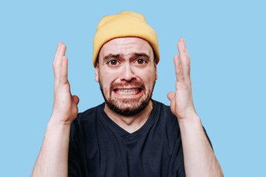 Sinirli bir insanın portresini yakından çek, içlerinden biri bir erkek, kameraya bakarken negatif bir duygu nöbetine kapılmış. Mavi arkaplanda stüdyo çekimi,