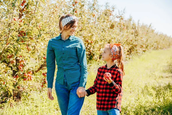 stock image the essence of family bonding as a mother and daughter walk hand in hand through the orchard, enjoying the bounty of nature. The warm sunlight, fresh air, and the company of loved ones