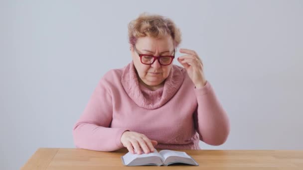 Kitap Okurken Evde Yorgun Üzgün Yaşlı Kadın Yorgunlukla Mücadele Ediyor — Stok video