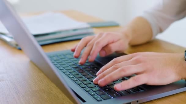 オフィスワークスペースのトップビューの視点からノートパソコンのキーボードを入力する男性の手のクローズアップ — ストック動画