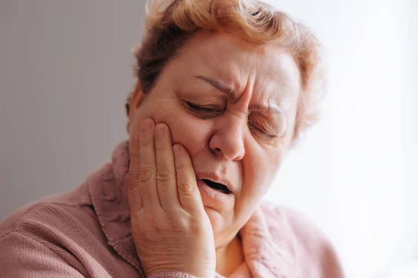 老年妇女牙痛真实的人 真实的症状 一个金发碧眼的女人 因严重的牙痛而面带微笑 看上去既痛苦又沮丧 — 图库照片