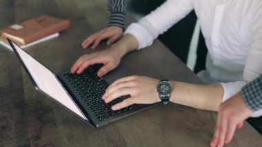 Ofis ortamında dizüstü bilgisayarlı bir klavyeye el atan bir adamın yakın çekimi. Etrafı kendi cihazlarıyla çevrili bir sürü insan var. Ofiste dizüstü bilgisayarda yazı yazan bir adamın el görüntüsü.