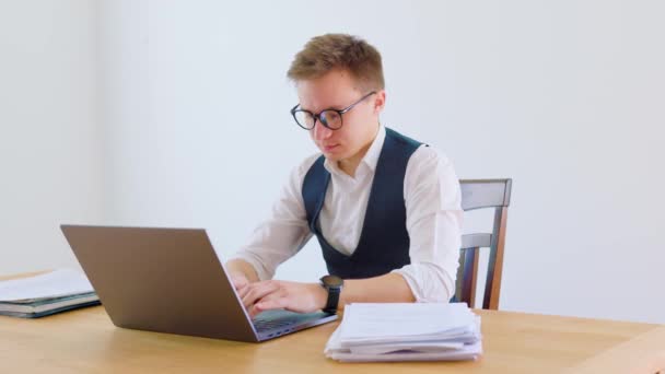 彼はノートパソコンに入力すると 彼の顔に満足そうな表情 彼は彼の机の上に座っています — ストック動画