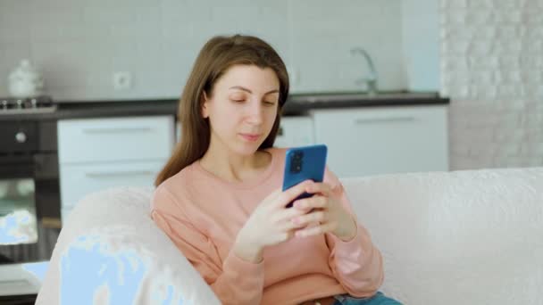 Una Joven Capturada Sentada Sofá Casa Absorta Lectura Smartphone Mientras — Vídeo de stock