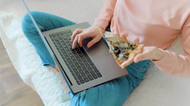 Een Vrouw Met Een Stuk Pizza Haar Hand Terwijl Studeert — Stockvideo