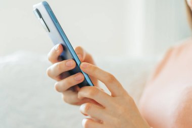 Kanepesinde oturup evinde rahat bir şekilde güzel bir kitabın tadını çıkarırken akıllı telefonunu elinde tutan bir insan eli haberleri okur..