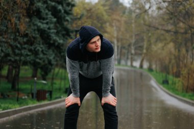 Yağmurlu Gün Yorgunluğu Yorgun Erkek Sporcu Açık Hava Çalışmasını Tamamlıyor. Yorgun ve yorgun bir erkek koşucu yağmurda dışarıda antrenman yaparken mola verir..