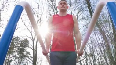 Genç Sporcular Başarıya Yolculuk 'ta Büyük Açık Hava Eğitimi. Keskin karın kasları ve güçlü pazılarıyla bu adam jimnastik eğitimi sırasında paralel barlarda hiç zorlanmadan sallanıyor.