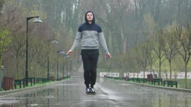 Yağmurlu Günler Jimnastik Antrenmanı Atlama İpi. Bu erkek sporcu, atlama halatı kullanarak açık hava antrenmanı sırasında atlama dayanıklılığını arttırırken yağmuru kucaklıyor..