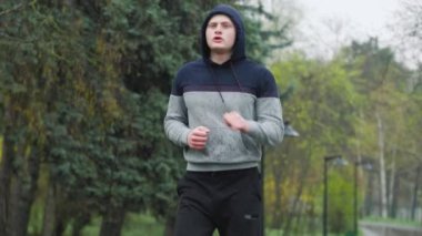 Açık Hava Eğitimi: Yağmurda Antrenman yaptıktan sonra yorgun bir erkek sporcu. Yağmurlu bir gün idmanı. Yağmurlu bir günde erkek koşucu kendini yorgun ve yorgun hissediyor..