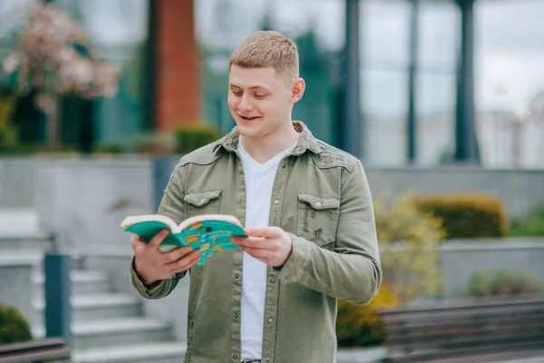 stock image Portrait of a happy blond boy reading a book, looking joyful and amazed. Studying in Style A Smiling Young Adult Reading with Satisfaction