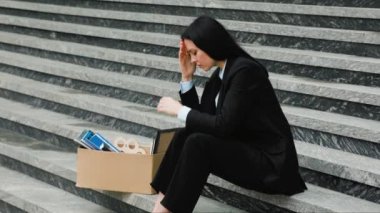 Esmer bir kadın merdivenlerde elleri başında oturuyor, işsizliğinin ve işsizliğinin ağırlığını hissediyor. Mutsuz Profesyonel İş Kaybından Sonra Merdivenlerde Oturuyor