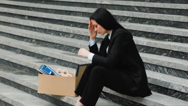 一个黑发女人双手抱头坐在楼梯上 感受着失业和失业带来的负担 失业后坐在楼梯上不快乐的专业人员 — 图库视频影像