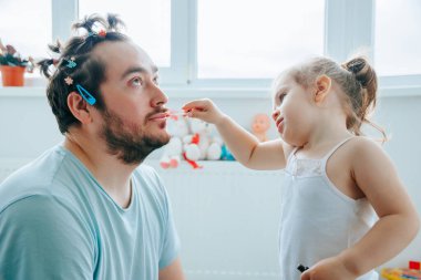 Sakallı bir baba ve kızı komik suratlar ve ifadelerle makyaj yaparken eğlenceli ve eğlenceli bir anı paylaşıyorlar. Babasının kızına ilk kez makyaj yapması korkunç bir şekilde yanlış gidiyor.