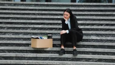 Depresyonda ve endişeli, profesyonel bir kadın eski işyerinin önünde oturuyor, işinden yeni kovulmuş. Kafkas Profesyonel Bakış Basamaklarda Depresif