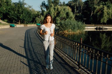 Gençlik Koşucusu, Spor Yolculuğu 'nda Pavement' i yumrukluyor. Yaşam tarzı olarak kazanan. Spor elbiseli güzel bir kadının koşu sırasında bitiş çizgisini geçerken gülümsemesinin yatay görüntüsü..