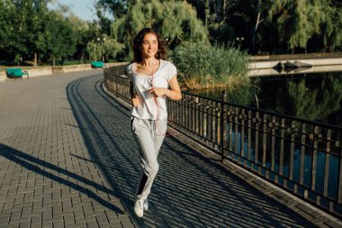 Spor Gençleri Sabah Koşusuyla Kalbini Pompaladı. Yaşam tarzı olarak kazanan. Spor elbiseli güzel bir kadının koşu sırasında bitiş çizgisini geçerken gülümsemesinin yatay görüntüsü..