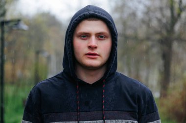 Rainy Outdoor 'da Çarpıcı Özellikleri Olan Gerçek İnsanlar Genç Erkek. Bir adamın çarpıcı portresi derisine yapışan yağmur damlalarını ve özelliklerini gösterir..