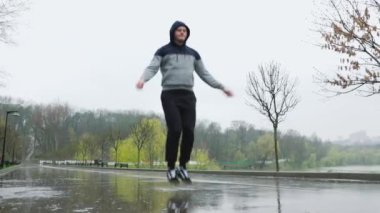 Yağmurlu Gün Atletizm Eğitimi Atlama İpi. Bardaktan boşanırcasına yağan yağmurda bile bu atletik erkek vücut yanığı için atlama halatını kullanmayı reddediyor..
