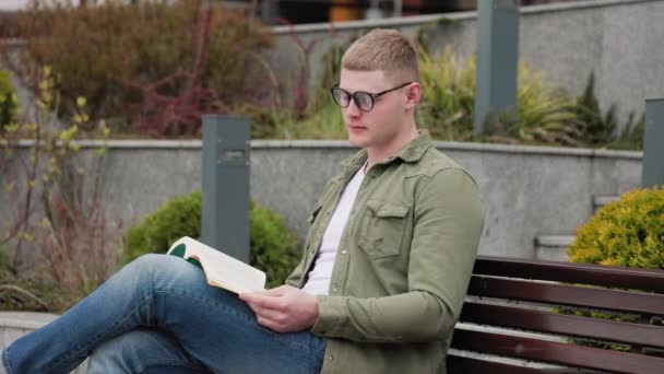 Молодой Взрослый Мужчина Читает Книгу Открытом Воздухе Наслаждаясь Красотой Природы — стоковое видео