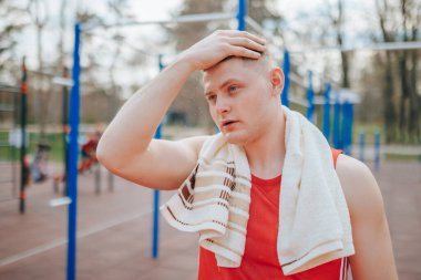 Yakışıklı genç adam dışarıda çalışmaya ara veriyor, alnında boncuk boncuk terliyor. Yakışıklı genç adam terli dışarıda çalışırken mola veriyor.