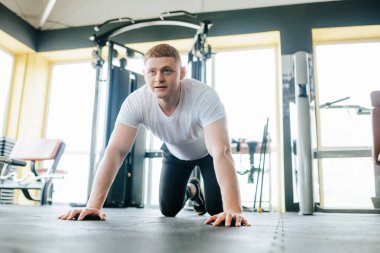 Spor salonundaki yoğun bir eğitimden sonra dinlenip iyileşen bir adam. Yorgun bir erkek sporcu, spor salonundaki sıkı egzersizden sonra soluklanır..