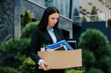 An image of a person holding a box, with a look of sadness and joblessness on their face. The Aftermath of Job Loss Woman Holding Box of Memories clipart