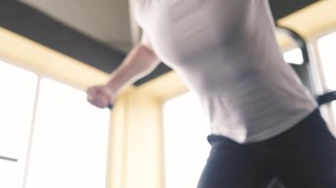 Genç bir adam spor salonunda ağırlık kaldırma makinesiyle antrenman yapıyor. Atletik performansını arttırmak için alt vücut kasları üzerinde çalışıyor..