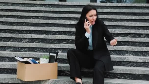 一个失业的女人 一边打电话一边拿着智能手机 心里很不高兴 失业妇女在电话中表达她的沮丧和忧虑 — 图库视频影像