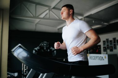 Formda bir adam spor kıyafetleriyle koşmak ve zıplamak da dahil olmak üzere bir dizi kardiyo çalışması yapıyor. Limits The Ultimate Gym and Run Sesion for Guys